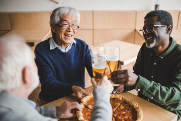 senior friends clinking glasses of beer