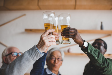 senior friends clinking glasses of beer