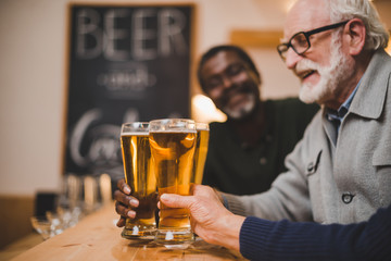senior friends clinking beer glasses