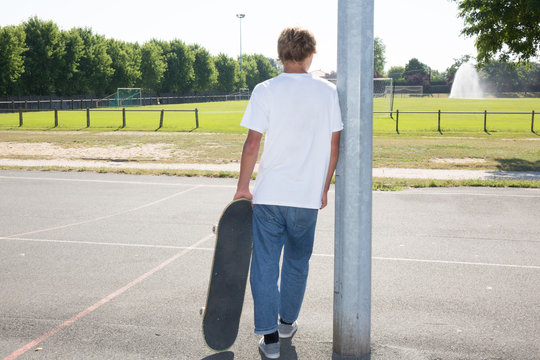 Blond Teenage Boy Relaxed With Skateboard Under Arm Hand