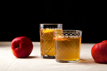 Two vintage glasses with apple cider on black background. Christmas beverages concept. Two red...