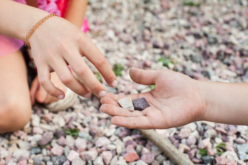 Little girl taking stones from friends hand. Concept of trust