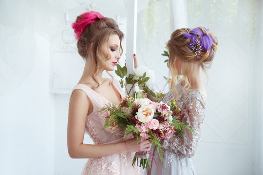 Two bride girls with hairdos with colored strands holding bouquets of flowers in their hands.