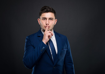 Handsome businessman doing silence gesture