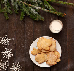 Christmas cookies on plate on wooden table with Christmas tree and a glass of milk