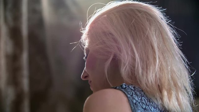 A young woman is sitting on the lap of his boyfriend and she is playing with her hair. 