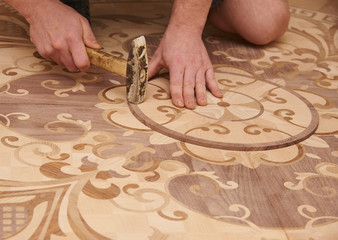 Fototapeta premium The carpenter installs one of the decorative elements of the parquet.
