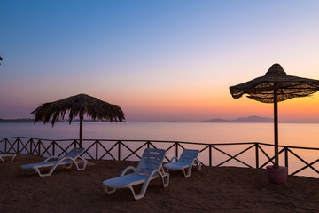 Beach umbrellas and sun lounger  at sunrise