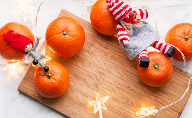 Happy christmas or new year card. New Year or Christmas decorations with mandarins and christmas lights on a cutting board on white surface. Preparation or celebration christmas or new year concept.