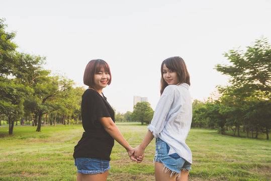LGBT lesbian women couple moments happiness. Lesbian women couple together outdoors concept. Lesbian couple holding hands together relation fall in love. Two asian women having fun together at park.
