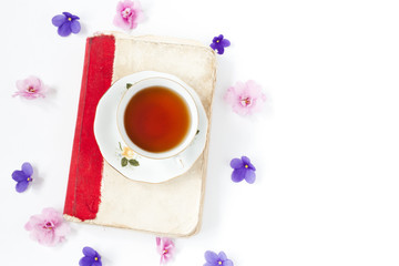 Old book with tea or coffee with flowers on white background .