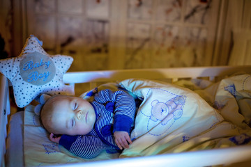 Adorable newborn baby boy, sleeping in crib at night © Tomsickova