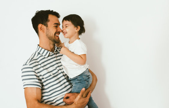 Funny Happy Dad And Daughter Play And Cuddle Together Against White Background. Good Relationship Of Parent And Child. Happy Family Moments Of Father And Toddler Girl. Childhood And Parenthood Care.