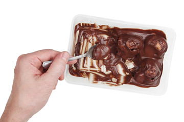 An elderly man eats chocolate dessert from a plastic box with a metal spoon