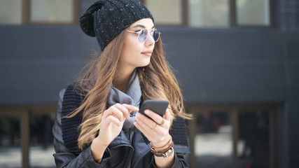 Beautiful young woman using mobile phone in outdoors