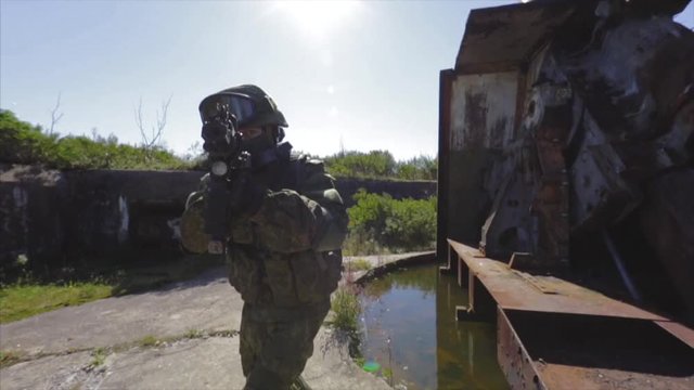 Soldier rapidly turning around and aiming with his automatic rifle near old AAA post.