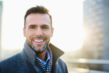 Portrait of happy man standing outdoors during sunny winter day