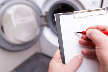 Plumber with clipboard near washing machine