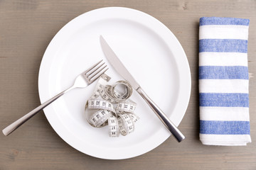 Plate with measuring tape, fork and knife. Dieting concept