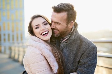 Portrait of happy couple hugging outdoors during sunny winter day