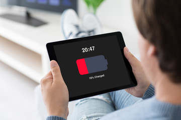 man holding computer tablet with low charged battery on screen