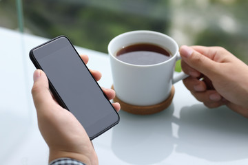 men hands holding phone with black screen and cup tea