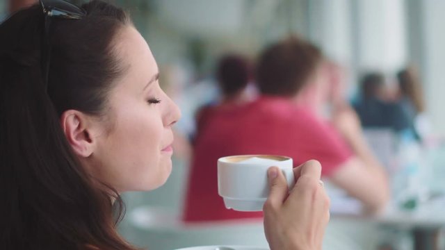 Adorable brunette enjoying her beverage in the restaurant - summer shot