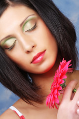 beautiful woman with bright make up holding pink gerber flower