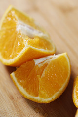 Closeup of fresh orange slices on a wooden cutting board.