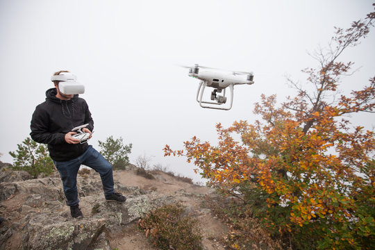 Young man handling drone, using virtual reality glasses.