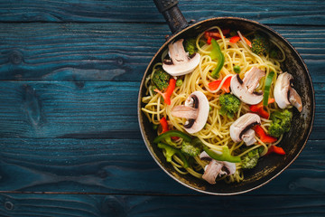 Noodles with vegetables in a frying pan. Asian Cuisine Pasta. Top view. Free space. On a wooden background.;