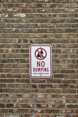 No dumping sign on a brick wall