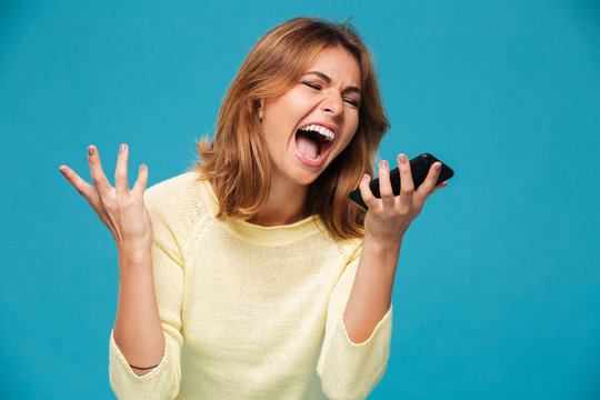 Angry woman in sweater screaming at smartphone