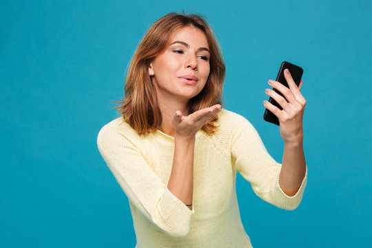Smiling woman in sweater making selfie on smartphone