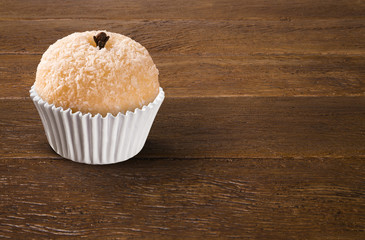 Traditional Brazilian sweet on wood background. Beijinho