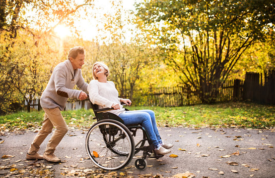 Senior Couple In Wheelchair In Autumn Nature.