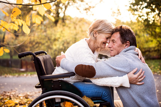 Senior couple in wheelchair in autumn nature.