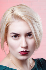 Close-up portrait of blonde with a bright lipstick red on a pink background
