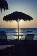 Beach umbrella and sun beds on the sea beach at sunset