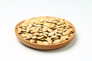 pumpkin seeds in wooden plate isolated on white background