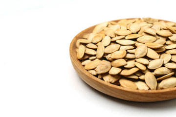 pumpkin seeds in wooden plate isolated on white background