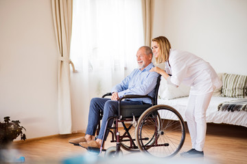 Nurse and senior man in wheelchair during home visit.