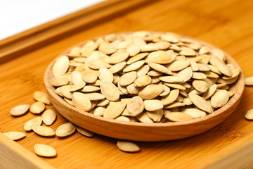 pumpkin seeds in wooden plate isolated on white background