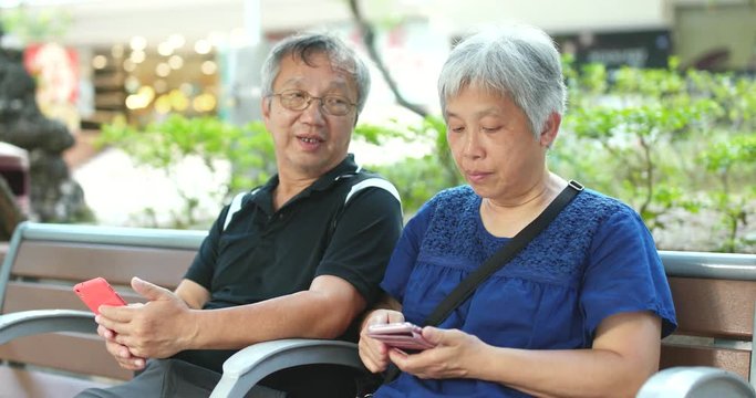 Retired couple use of mobile phone at street
