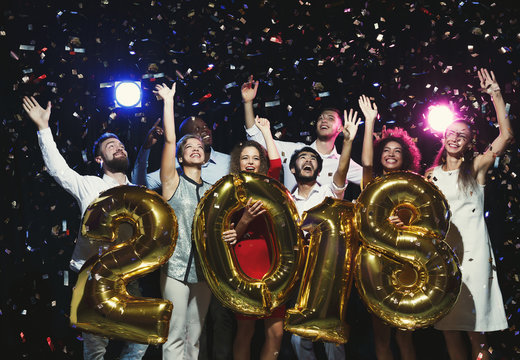 Group of young happy friends with number balloons at new year party