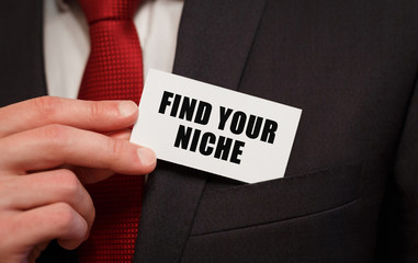 Businessman putting a card with text FIND YOUR NICHE in the pocket