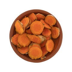 Top view of a small red clay bowl filled with slices of fresh turmeric isolated on a white background.