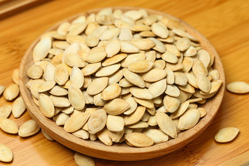 pumpkin seeds in wooden plate isolated on white background