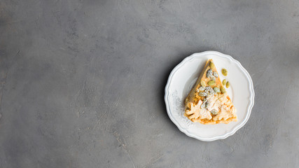 Autumn background with pumpkin pie on a white plate. A autumn gray concrete background for you. Copy Space. Place for text. Flat lay, top view