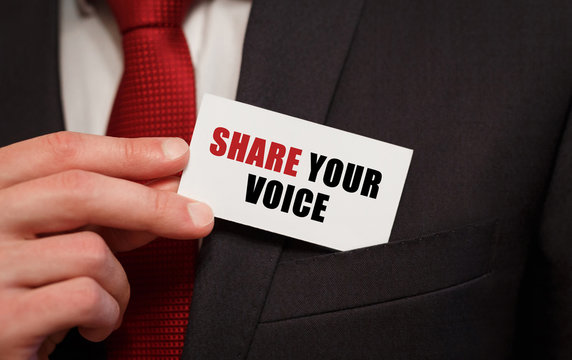 Businessman putting a card with text SHARE YOUR VOICE in the pocket